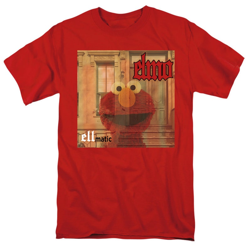 Puede incluir: Camiseta roja con un gr&aacute;fico de Elmo de Plaza S&eacute;samo. El gr&aacute;fico es una foto de estilo vintage de Elmo frente a un edificio con el texto "Elmo" y "ellmatic" en la camiseta.