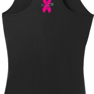 May include: Black tank top with a pink ribbon and safety pin graphic.