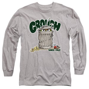 May include: A gray long-sleeve t-shirt with a green, white, and black illustration of Oscar the Grouch from Sesame Street. Oscar is inside a trash can with the text "Grouch" above him and "Since 1969" below him.