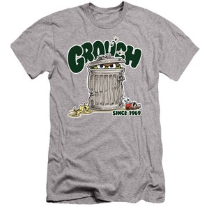 May include: A grey t-shirt with a green cartoon character peeking out of a trash can. The text "GROUCH SINCE 1969" is printed on the shirt.