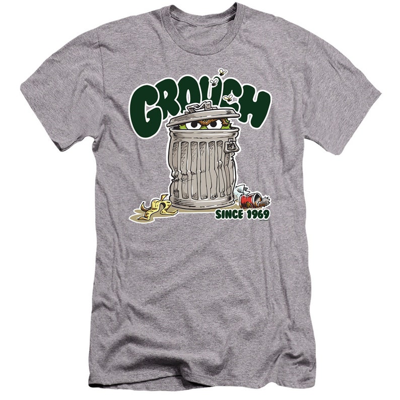 May include: A gray t-shirt with a green "GROUCH" graphic. The graphic features Oscar the Grouch from Sesame Street peeking out of a trash can with the text "SINCE 1969".