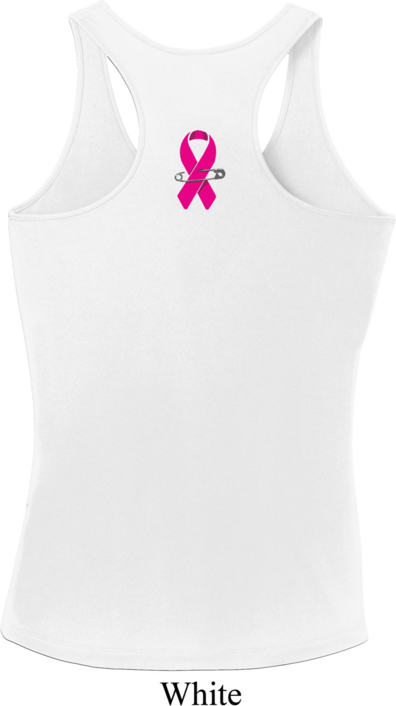 May include: White tank top with a pink ribbon and a safety pin on the back.