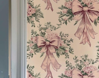 Könnte beinhalten: Eine hellblaue Tür mit weißem Rahmen ist teilweise geöffnet und gibt den Blick auf einen Raum mit einer Tapete frei, die ein sich wiederholendes Muster aus rosa Schleifen und Blumensträußen auf cremefarbenem Hintergrund zeigt.