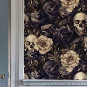 May include: A dark grey door with a light blue door panel and a gold door handle is partially open. The wall behind the door is covered in a dark floral wallpaper with white flowers and skulls.