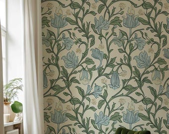 May include: A green velvet armchair sits in a room with a floral wallpaper featuring a repeating pattern of blue flowers and green leaves. A brown dog sits on the floor in front of the chair.