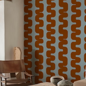 Può includere: Una stanza con carta da parati a motivi ondulati blu chiaro e arancione. Una sedia in pelle marrone, un tavolino in legno e ciotole decorative sono in primo piano. La stanza ha una palette di colori neutri.