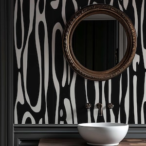May include: A bathroom vanity with a white ceramic sink, brass fixtures, and a round, ornate mirror. The black wall features a white, organic pattern. The vanity is dark wood with drawers.