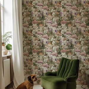 May include: A green velvet armchair sits in a room with white walls and a mushroom-themed wallpaper. A brown dog sits on the floor in front of the chair.
