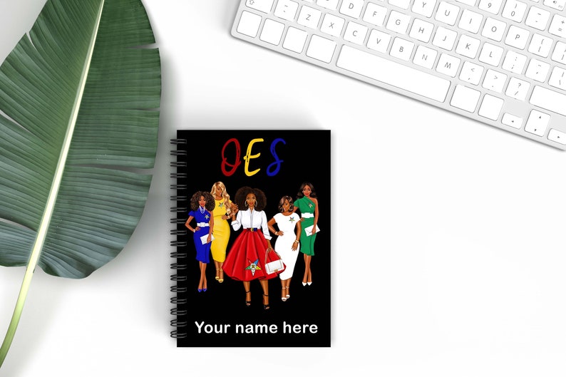 May include: Black spiral-bound notebook featuring a colorful illustration of five women in dresses. The word "OES" is written in red, yellow, and blue above the illustration. The text "Your name here" is at the bottom.