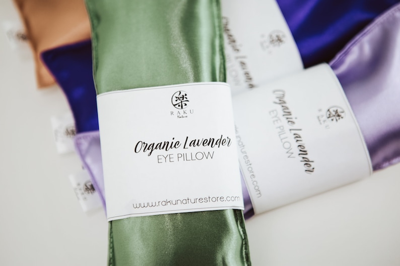 Puede incluir: Almohadas para ojos de sat&eacute;n verde, morado y marr&oacute;n con etiquetas blancas. La etiqueta de la almohada para ojos verde dice "Organic Lavender Eye Pillow" y "www.rakunaturestore.com".