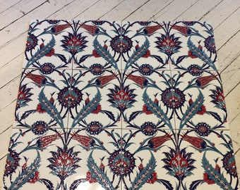 May include: Nine white ceramic tiles arranged in a square, featuring a repeating floral pattern. The design includes red, blue, and teal flowers and leaves. The tiles are likely for decorative use, such as a backsplash or wall accent.