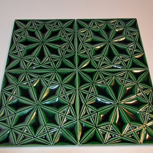Op de afbeelding: Vier vierkante groene keramische tegels met een geometrisch sterrenpatroon. De tegels hebben een glanzende afwerking en een verhoogd, driedimensionaal ontwerp. Het donkergroene en zwarte kleurenschema cre&euml;ert een opvallend contrast, geschikt voor interieurdecoratie.