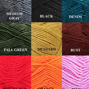 May include: A collection of yarn skeins in various colors, including natural white, light gray, light brown, medium gray, black, denim, fall green, mustard, rust, bright red, orange, pink, cherry, navy blue, and turquoise. Each skein has a label with the color name.