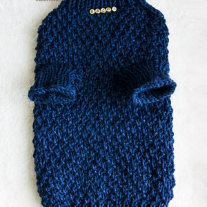 May include: A navy blue knitted pet sweater with a high collar and armholes. The sweater has the name "SACHA" spelled out in small gold beads. The item is handmade and designed for cats.