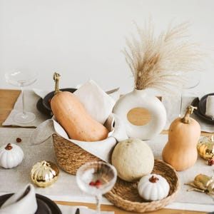 Eco-friendly white linen table runner laid across a modern wooden table. Also this natural linen table runner makes a perfect housewarming gift or timeless addition to a modern, minimalist kitchen or dining room.