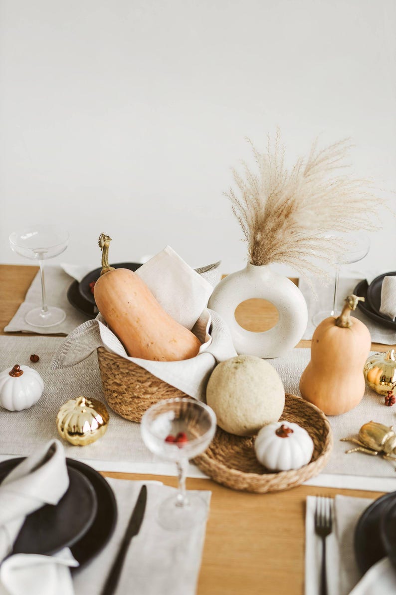 Eco-friendly white linen table runner laid across a modern wooden table. Also this natural linen table runner makes a perfect housewarming gift or timeless addition to a modern, minimalist kitchen or dining room.