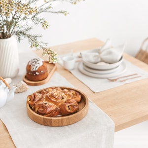 Beige and light-toned table setting idea with a herringbone white table runner, placemat, and napkin, combined with white plates and copper-colored tableware and wooden serving plates