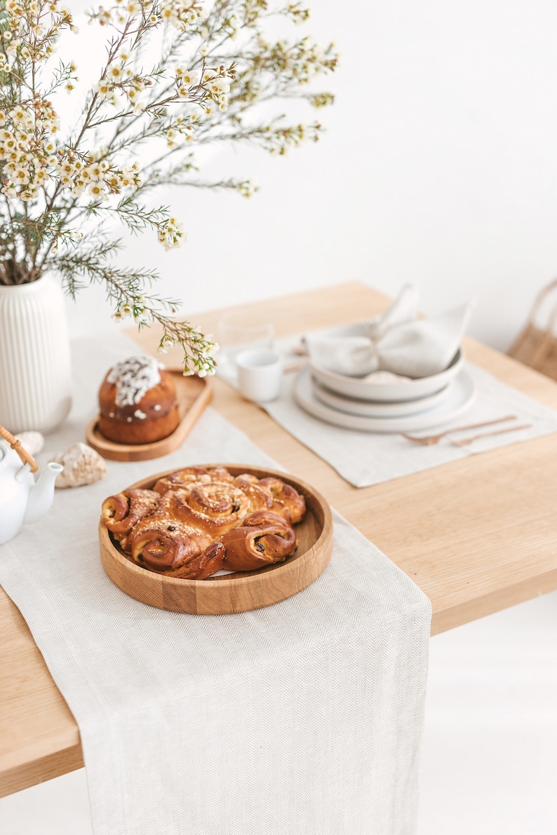 Beige and light-toned table setting idea with a herringbone white table runner, placemat, and napkin, combined with white plates and copper-colored tableware and wooden serving plates