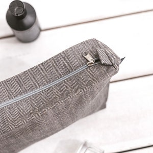 Large grey linen makeup bag in a herringbone pattern, with a zipper, from the top