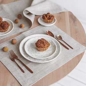 A table set with modern white linen placemats mixed with the same color table runner, creating a cozy and warm home environment