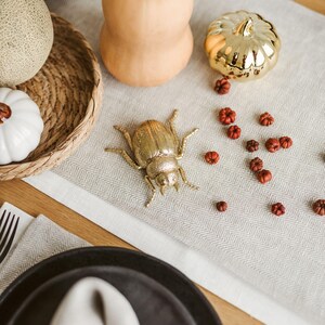 Long white linen table runner used as Thanksgiving or Christmas centerpiece base. Eco-friendly white linen table runner laid across a modern wooden table. Also this natural linen table runner makes a perfect housewarming gift or timeless addition to a modern, minimalist kitchen or dining room.