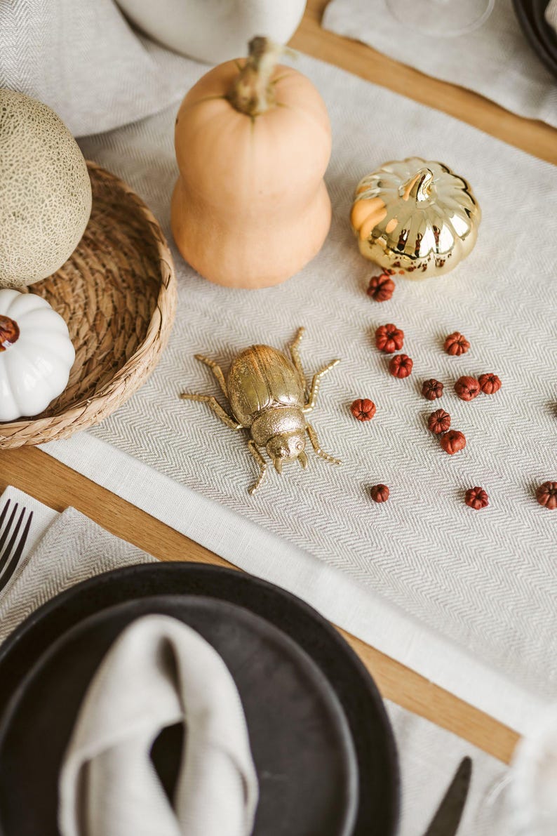 Long white linen table runner used as Thanksgiving or Christmas centerpiece base. Eco-friendly white linen table runner laid across a modern wooden table. Also this natural linen table runner makes a perfect housewarming gift or timeless addition to a modern, minimalist kitchen or dining room.