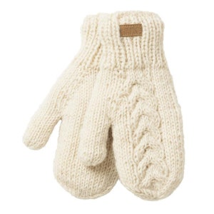 May include: A pair of cream-coloured knitted mittens. One mitten features a cable knit pattern. The mittens have a ribbed cuff and a small brown leather tag with the letters "ark". The mittens are made of a thick, warm yarn, perfect for cold weather.