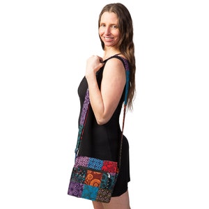 May include: A black sleeveless dress with a colorful patchwork crossbody bag. The bag has a long strap and a flap closure.