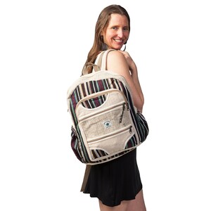 May include: A beige hemp backpack with a striped pattern in shades of brown, black, and green. The backpack has multiple pockets and a zipper closure. The backpack has a green leaf logo with the text "Hemptique" on it.