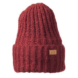 May include: A burgundy knit beanie with a ribbed design. The hat features a folded brim and a small, rectangular leather patch with the word "ark" on it. The hat is made of a thick, warm material.