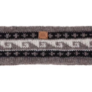 Könnte beinhalten: Grau, weiß und schwarz gestricktes Stirnband mit geometrischem Muster. Das Stirnband hat ein kleines braunes Lederetikett mit den Buchstaben "ARK". Das Design umfasst Wellen- und Blumenmotive.