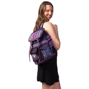 May include: A purple and pink patterned backpack with a large front pocket and adjustable straps. The backpack is made of a woven fabric and has a bohemian style.