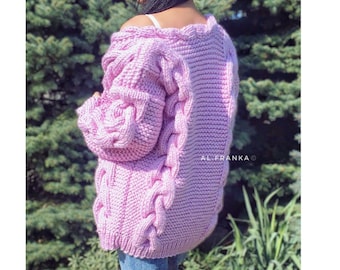 May include: A light pink cable knit cardigan with a chunky knit texture. The cardigan has a V-neck and long sleeves.