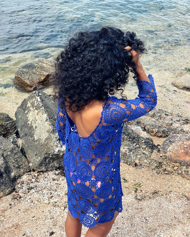 K&ouml;nnte beinhalten: Ein blaues H&auml;kelkleid mit einem gewellten Saum und langen &Auml;rmeln. Das Kleid ist aus einem leichten, luftigen Stoff gefertigt und perfekt zum Tragen &uuml;ber einem Badeanzug.