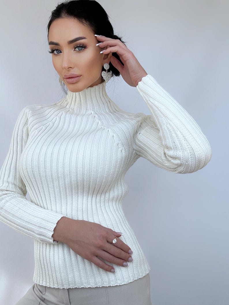 May include: A white ribbed turtleneck sweater with long sleeves.