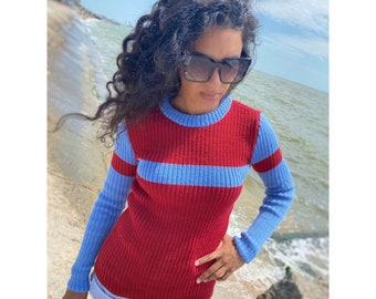 May include: A red and blue striped sweater with long sleeves. The sweater is ribbed and has a crew neck.