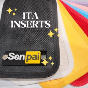 May include: A close-up of a black mesh fabric with the text "ITA INSERTS" and a yellow label with the text "Senpai". The fabric is surrounded by a variety of colored fabrics, including white, yellow, red, blue, and pink.