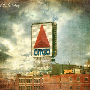 May include: A vintage-style image of a large red triangle sign with the word "CITGO" in blue letters. The sign is mounted on a tall structure and is surrounded by a cloudy sky and a cityscape.
