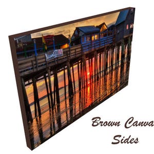 Pu&ograve; includere: Un molo di legno colorato con edifici in cima si estende sull'acqua al tramonto. L'acqua riflette i colori arancioni e rosa del cielo. Il molo &egrave; sostenuto da pali di legno. Il testo "Happy Hours" &egrave; visibile su un cartello.