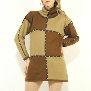 May include: A brown and beige sweater dress with a geometric pattern and gold accents. The dress has a turtleneck and long sleeves.