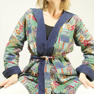 Peut inclure: Une veste à capuche à motif vert, rouge et bleu avec une bordure bleu marine et une ceinture à nouer. La veste est faite d'un tissu doux et confortable et a une coupe décontractée.