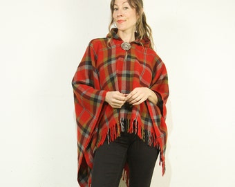 May include: Red and black plaid hooded poncho with fringe trim. The poncho is made of a soft, warm fabric and has a relaxed fit.