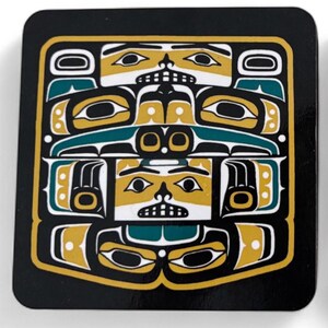 Puede incluir: Posavasos cuadrado con un dise&ntilde;o nativo americano. El posavasos presenta un fondo negro con un patr&oacute;n geom&eacute;trico amarillo y verde azulado. El dise&ntilde;o incluye caras y formas estilizadas, creando un aspecto audaz y art&iacute;stico. El posavasos probablemente est&aacute; hecho de un material duradero.