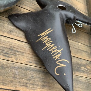 May include: Black bird-shaped wall decor with a gold inscription that reads "Marquetry."
