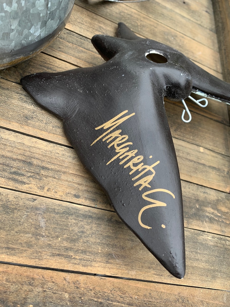 May include: Black bird-shaped wall decor with a gold inscription that reads "Marquetry."