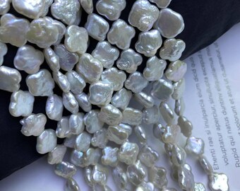 Peut inclure: Gros plan sur des rangées de perles baroques blanches. Les perles ont une forme irrégulière et organique, avec un éclat nacré. Les perles sont enfilées, ce qui suggère leur utilisation dans la création de bijoux, comme des colliers ou des bracelets.