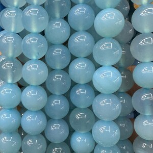 May include: Strands of light blue, round gemstone beads. The beads have a smooth, polished surface and are strung together, creating a shimmering effect. The beads are a soft, translucent color, perfect for jewelry making.