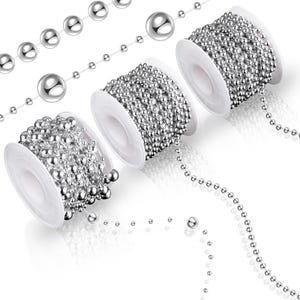 May include: Several spools of silver ball chain are displayed against a white background. The chain is unwound in sections, showing individual beads. The spools are white and the beads are shiny and reflective. The chains are used for jewelry making and crafts.