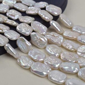 May include: Close-up of a strand of lustrous, irregular-shaped white pearls. The pearls have a subtle iridescent sheen, reflecting light. The beads are strung together, suggesting they are ready for jewelry making.