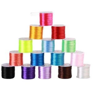 May include: A pyramid of colorful elastic string spools in various colors, including red, yellow, green, blue, pink, and black. The spools are neatly stacked, showcasing the vibrant hues of the elastic cord.